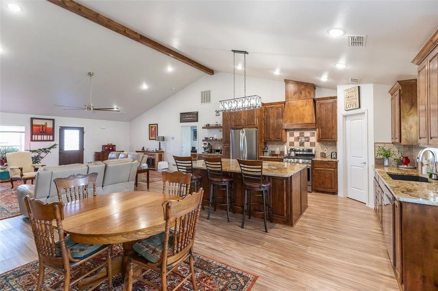 Open-concept living space featuring a vaulted ceiling with exposed wood beams Open-concept living space featuring a vaulted ceiling with exposed wood beams