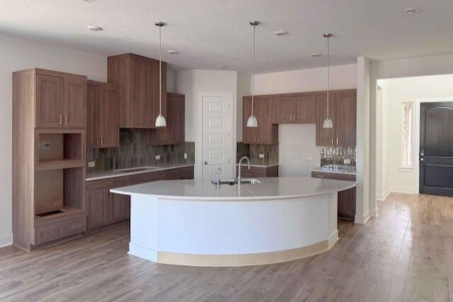 Kitchen featuring a large island with sink, light wood finished floors, wood finish cabinets, and a kitchen breakfast bar