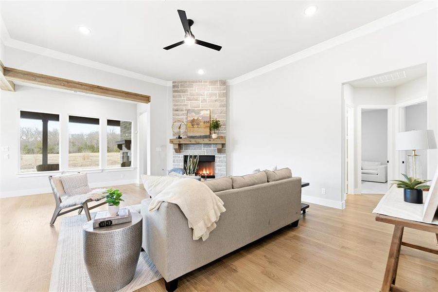 Living area with a large fireplace, crown molding, a ceiling fan, light wood-type flooring, and recessed lighting