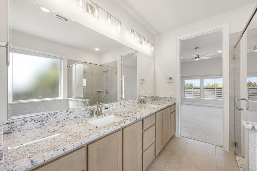 Master bathroom with double vanity, granite countertops, glass shower, and tile floors