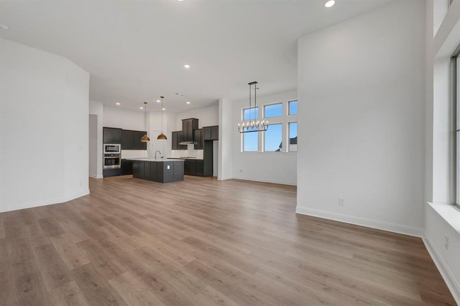 Unfurnished living room with a chandelier and light wood-style flooring