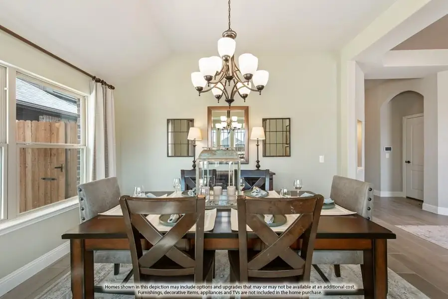 Dining room with dark wood table, upholstered chairs, chandelier, and vaulted ceiling near large window