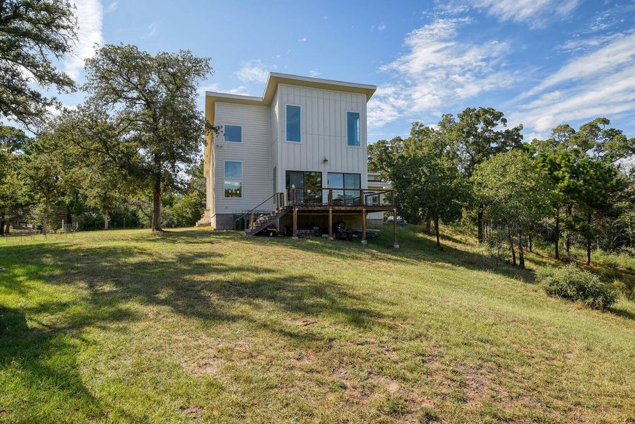 Rear view of property featuring board and batten siding, stairs, a wooden deck, and a yard Rear view of property featuring board and batten siding, stairs, a wooden deck, and a yard