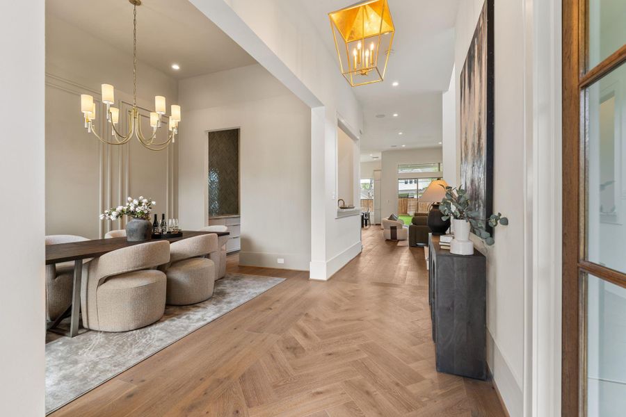 The main hallway transitions effortlessly from the entry into the heart of the home, showcasing continuous hardwood flooring, soft neutral tones, and an open layout that connects formal and casual living areas.