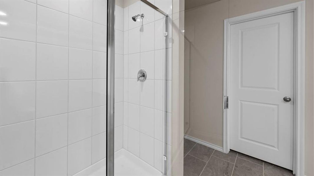 Glass-enclosed shower with white tiled walls and a chrome showerhead Glass-enclosed shower with white tiled walls and a chrome showerhead
