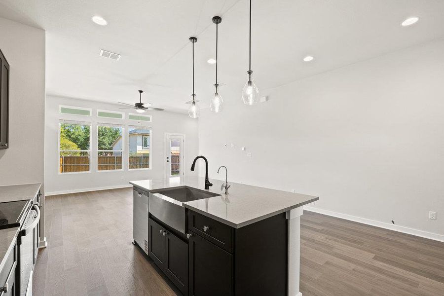 Kitchen featuring dark cabinetry, an island with sink, dark wood-type flooring, appliances with stainless steel finishes, and open floor plan