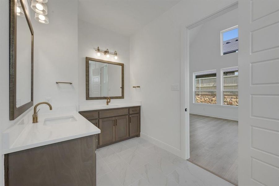 Dual vanity bathroom featuring white countertops, undermount sinks, and bronze-finish fixtures