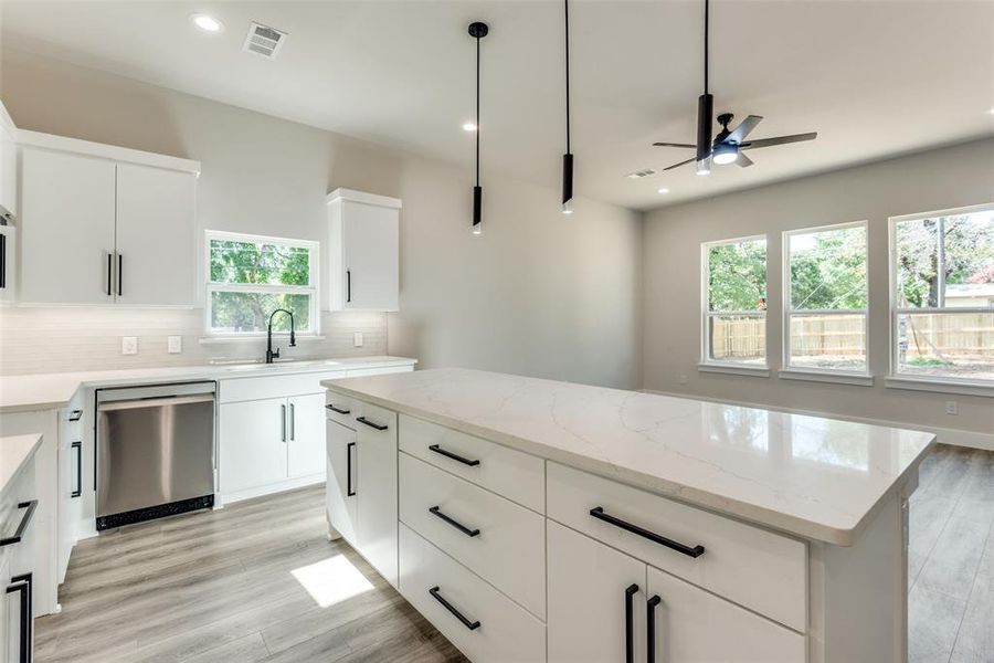 Kitchen with a healthy amount of sunlight, backsplash, pendant lighting, and stainless steel dishwasher