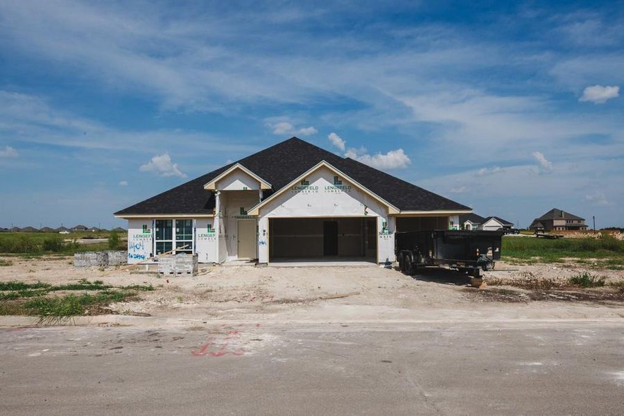 Property under construction featuring dirt driveway, an attached garage, and a shingled roof Property under construction featuring dirt driveway, an attached garage, and a shingled roof