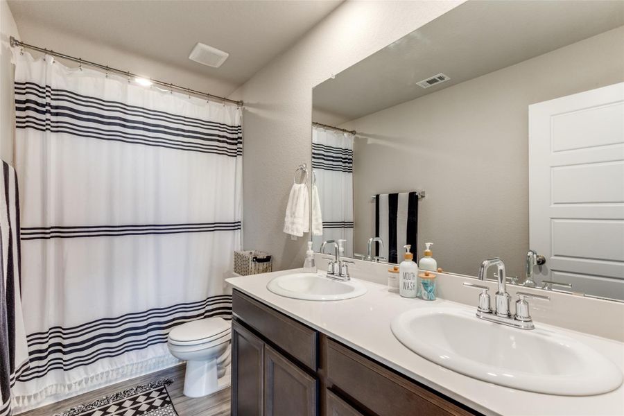 Full bath featuring double vanity, dark wood-style floors, and a shower with curtain