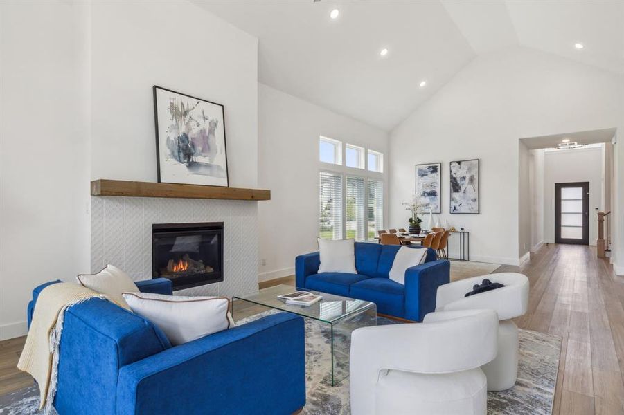 Living room featuring light hardwood / wood-style floors, a tile fireplace, and high vaulted ceiling