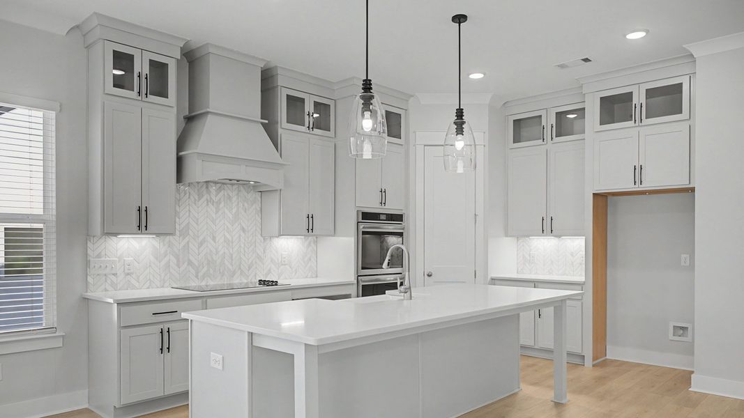 Kitchen with floor to ceiling cabinets, quartz countertops, tile backsplash, and vent hood