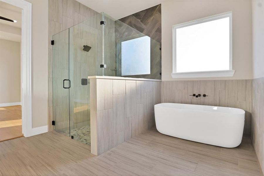 Bathroom with wood-type flooring, separate shower and tub, and tile walls