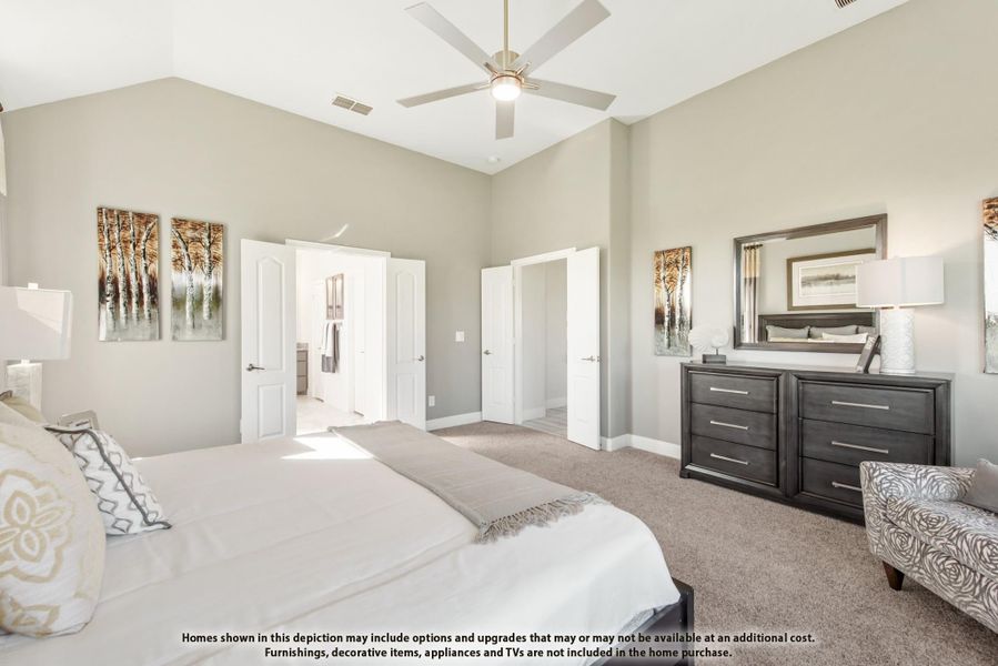 Master bedroom with vaulted ceiling, ceiling fan, carpet flooring, dark wood dresser, and doors leading to bathroom and closet.