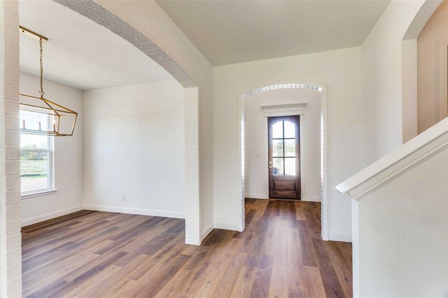 Entrance foyer with a chandelier, plenty of natural light, and dark wood-type flooring