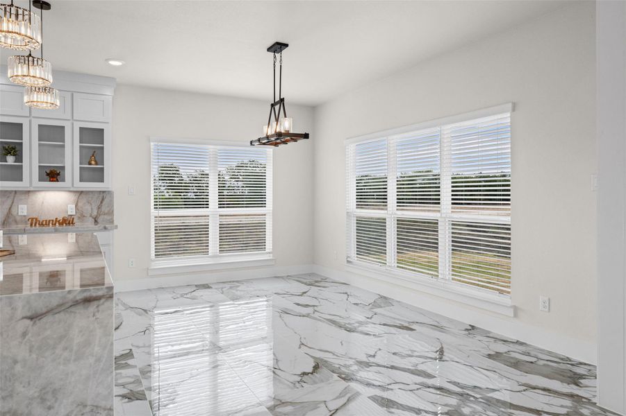 Polished tile flooring and large windows create a bright atmosphere in this spacious dining area.
