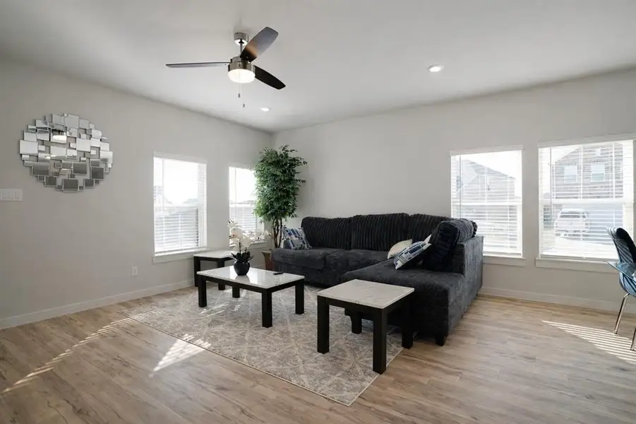 Living area with light wood finished floors, healthy amount of natural light, ceiling fan, and recessed lighting