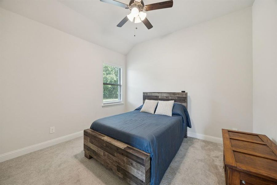 Secondary bedroom featuring lofted ceiling, carpet floors, and ceiling fan.