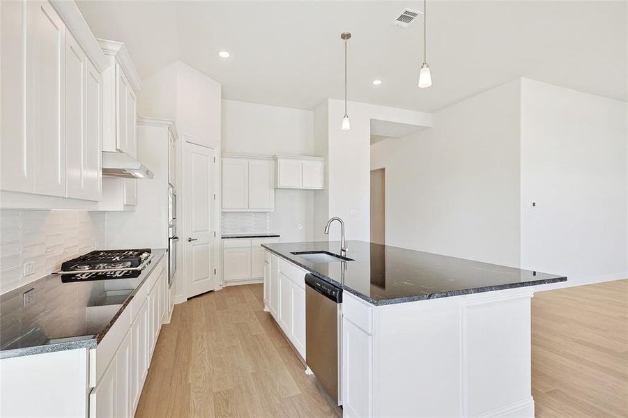 Kitchen featuring light hardwood / wood-style floors, backsplash, sink, and white cabinetry