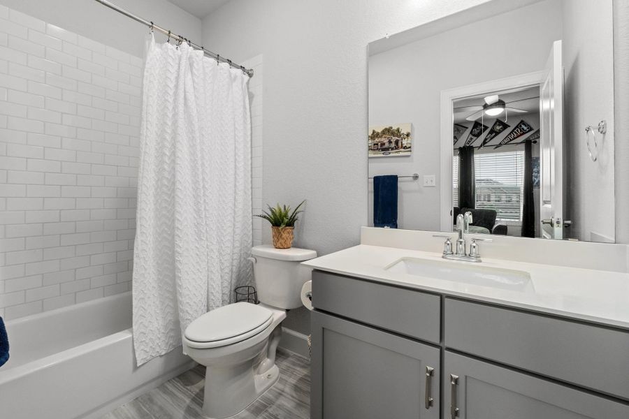 Ensuite bathroom with ceiling fan, connected bathroom, vanity, toilet, and shower / tub combo with curtain Ensuite bathroom with ceiling fan, connected bathroom, vanity, toilet, and shower / tub combo with curtain