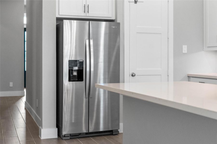 Kitchen comes equipped with a side-by-side Whirlpool refrigerator.