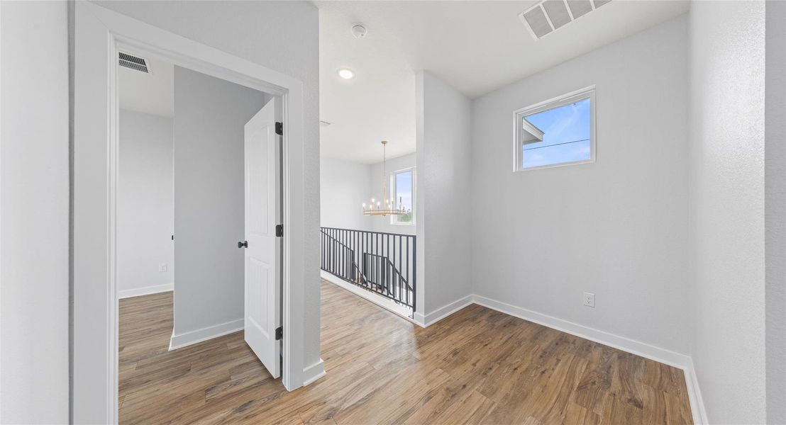 Corridor with wood finished floors, a chandelier, an upstairs landing, and recessed lighting