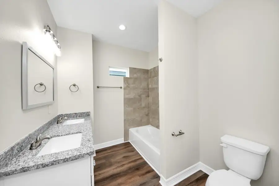This secondary hall bathroom is both stylish and functional, featuring durable LVP flooring, granite countertops with dual sinks, and plenty of storage space—perfect for family use and guests alike - (representation photo).