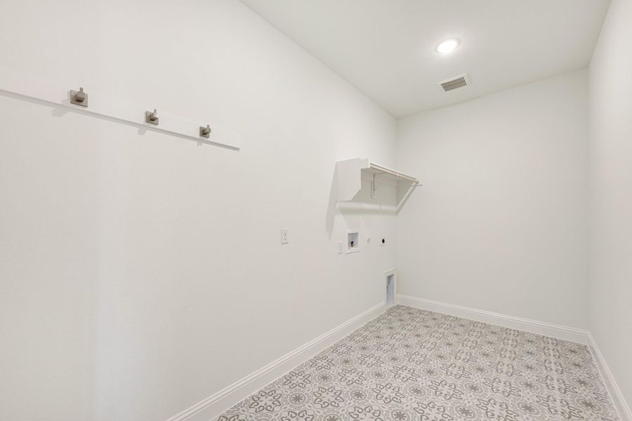 Laundry room with patterned tile floor, wall hooks, upper shelf, and washer and dryer hookups Laundry room with patterned tile floor, wall hooks, upper shelf, and washer and dryer hookups