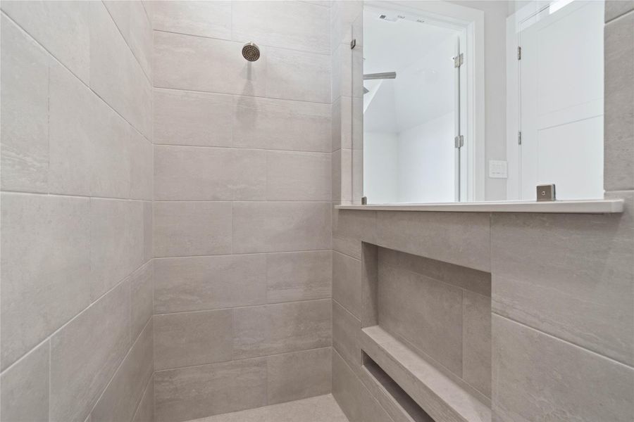 Indulge in the spa-like luxury of this primary bathroom, featuring a stunning walk-in shower adorned with tile surround and a sleek showerhead.