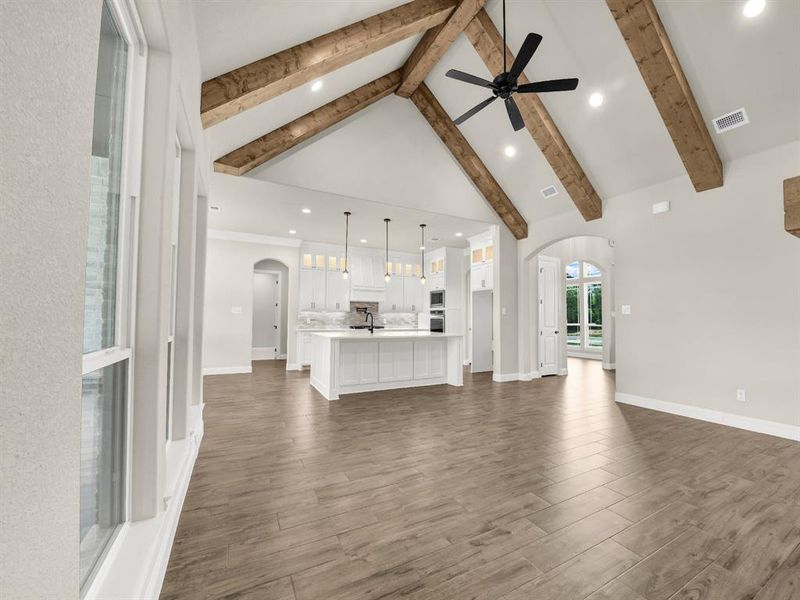 Unfurnished living room featuring arched walkways, a sink, a ceiling fan, high vaulted ceiling, and beam ceiling Unfurnished living room featuring arched walkways, a sink, a ceiling fan, high vaulted ceiling, and beam ceiling
