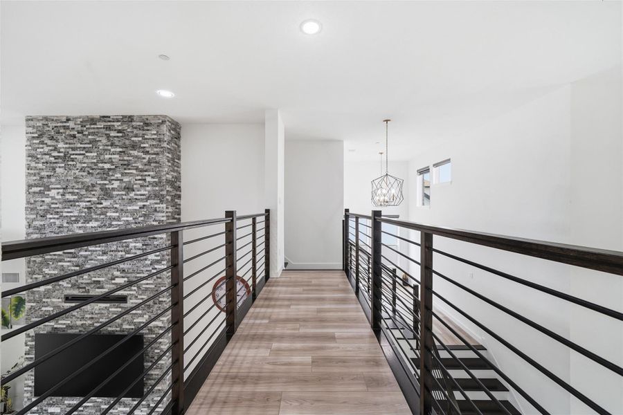 The property features a modern hallway with light wood-style flooring and sleek metal railings