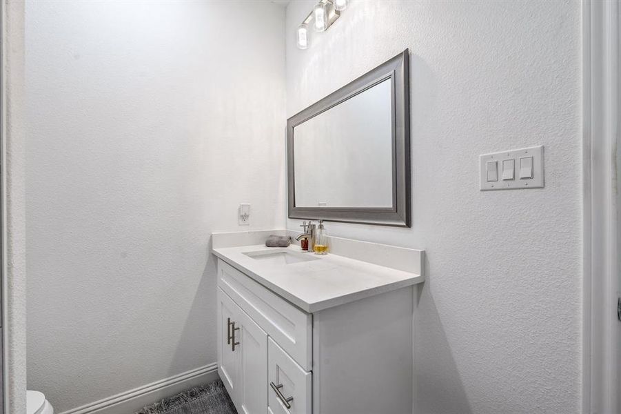 Half bathroom with a textured wall and vanity