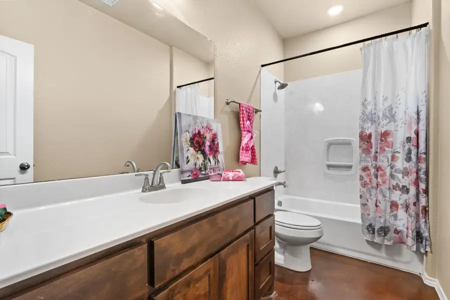 Bathroom featuring shower / bathtub combination with curtain, vanity, and finished concrete flooring