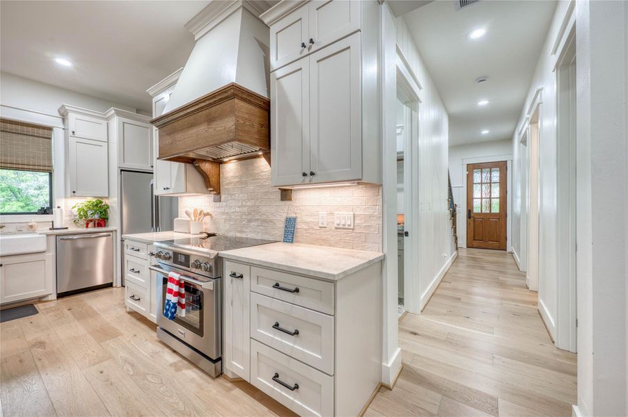 Kitchen featuring white shaker cabinetry, light-toned wood-finish flooring, and stainless steel appliances