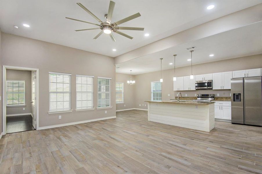 Kitchen with stainless steel appliances, a ceiling fan, light wood-style flooring, recessed lighting, and white cabinets