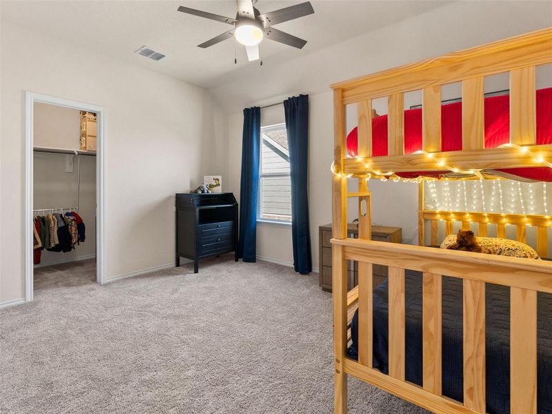 Bedroom with a walk in closet, light carpet, and a ceiling fan