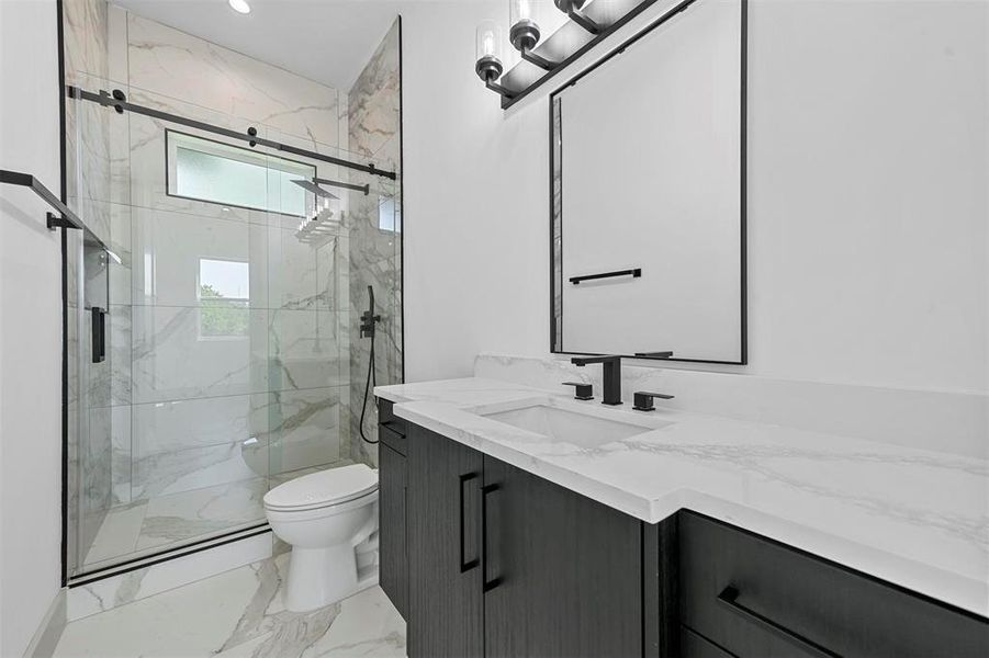 Bathroom featuring a shower with shower door, vanity, tile patterned floors, and toilet