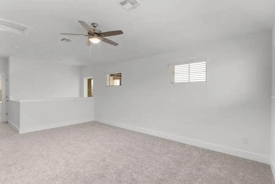 A versatile open loft area provides additional living space, featuring soft carpet flooring and abundant natural light.