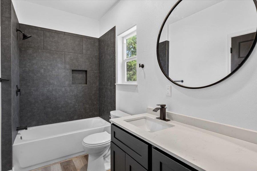 Full bathroom between 2 secondary bathrooms. Crisp white walls contrast with dark stone tiling in this contemporary bathroom space. Full bathroom between 2 secondary bathrooms. Crisp white walls contrast with dark stone tiling in this contemporary bathroom space.