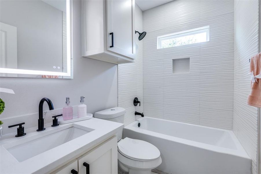 Full bathroom featuring toilet, tiled shower / bath, and vanity