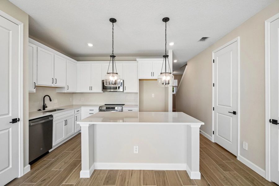 Kitchen with our AW Collection® Harmony has a large island and stainless steel microwave, dishwasher and oven