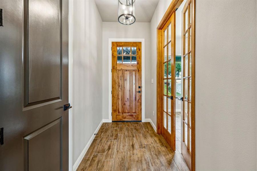 Entryway with light wood-type flooring, an inviting chandelier, and french doors