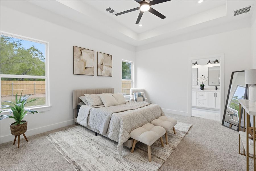 Bedroom with light colored carpet, a ceiling fan, a tray ceiling, recessed lighting, and connected bathroom