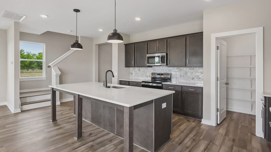 Kitchen with dark cabinetry, quartz countertops, pendant lighting, and tile backsplash Kitchen with dark cabinetry, quartz countertops, pendant lighting, and tile backsplash