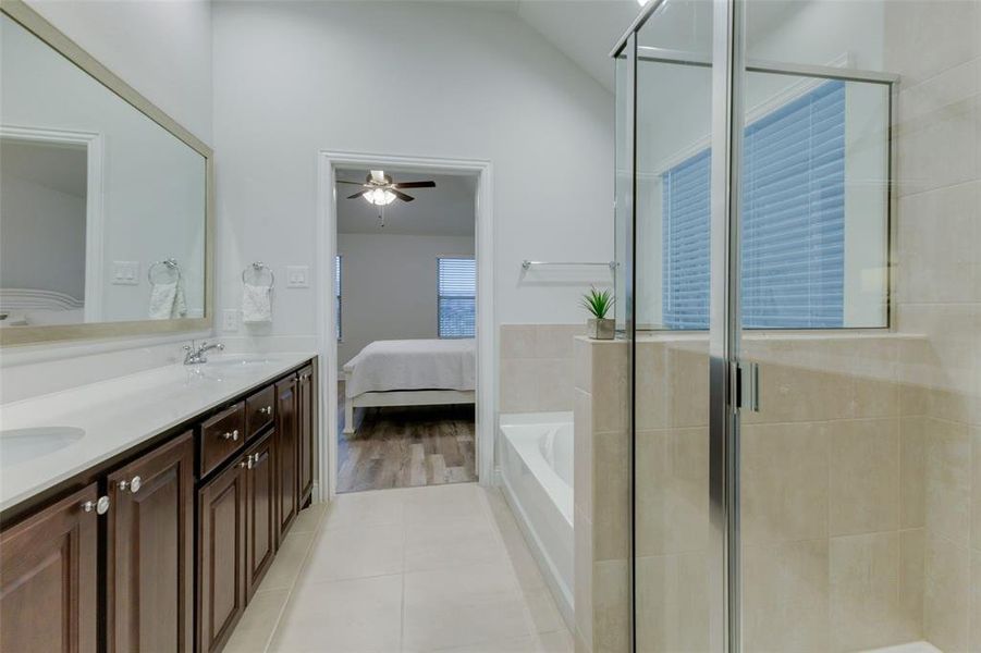 Bathroom with vanity, shower with separate bathtub, vaulted ceiling, ceiling fan, and hardwood / wood-style floors