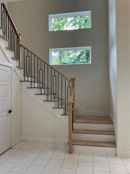 Stairs with light tile patterned flooring and a towering ceiling