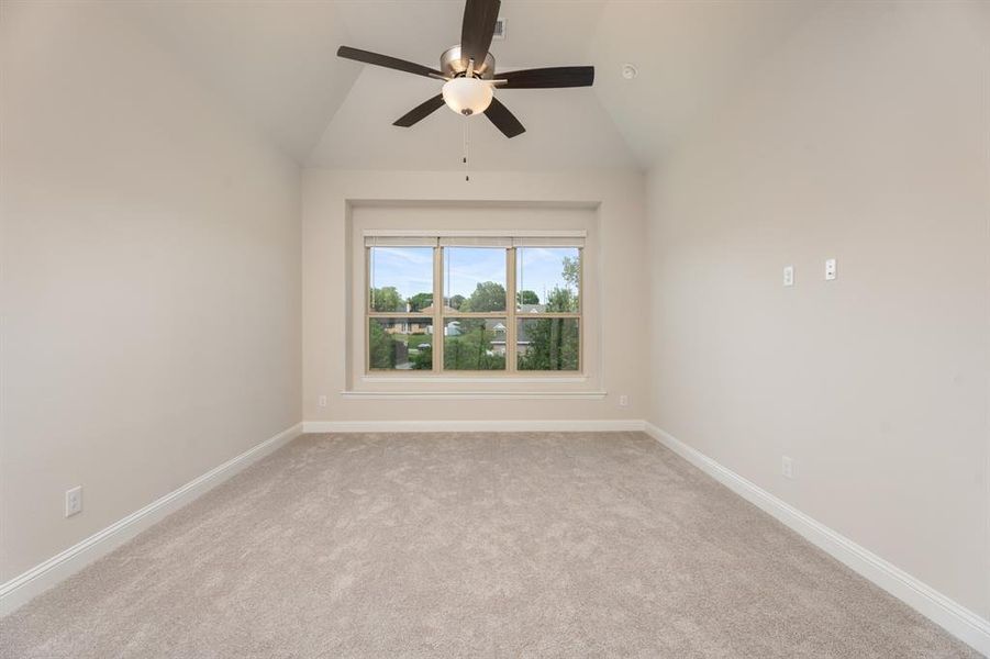 Empty room with light colored carpet, ceiling fan, and vaulted ceiling