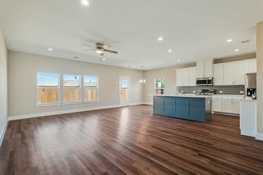 Kitchen featuring decorative backsplash, dark hardwood / wood-style flooring, stainless steel appliances, pendant lighting, and white cabinetry Kitchen featuring decorative backsplash, dark hardwood / wood-style flooring, stainless steel appliances, pendant lighting, and white cabinetry