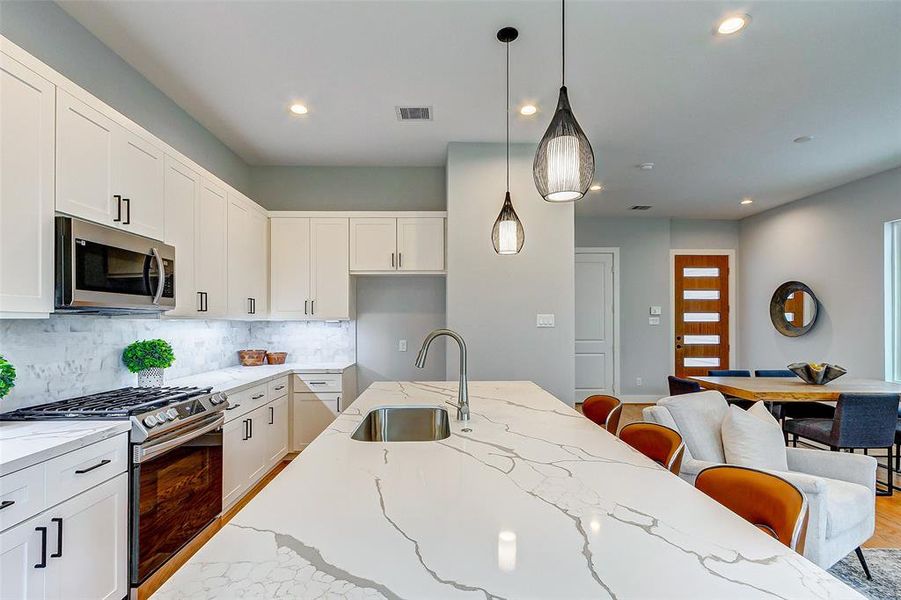 Elegant kitchen makes for the perfect place to cook and entertain with friends and family. Notice the under cabinet lighting and real marble backsplash.