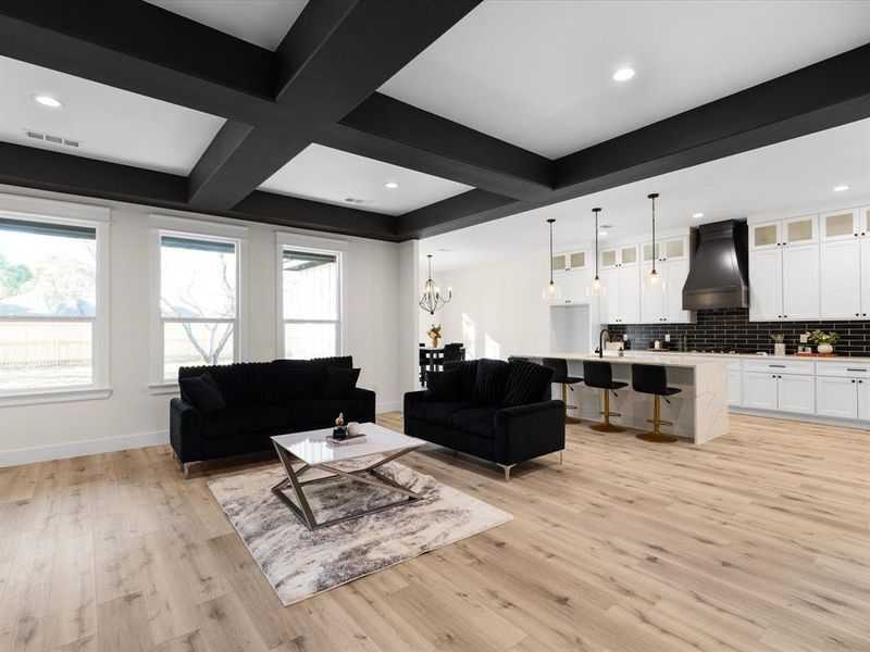 Living room with coffered ceiling, light wood-style floors, and hanging lights